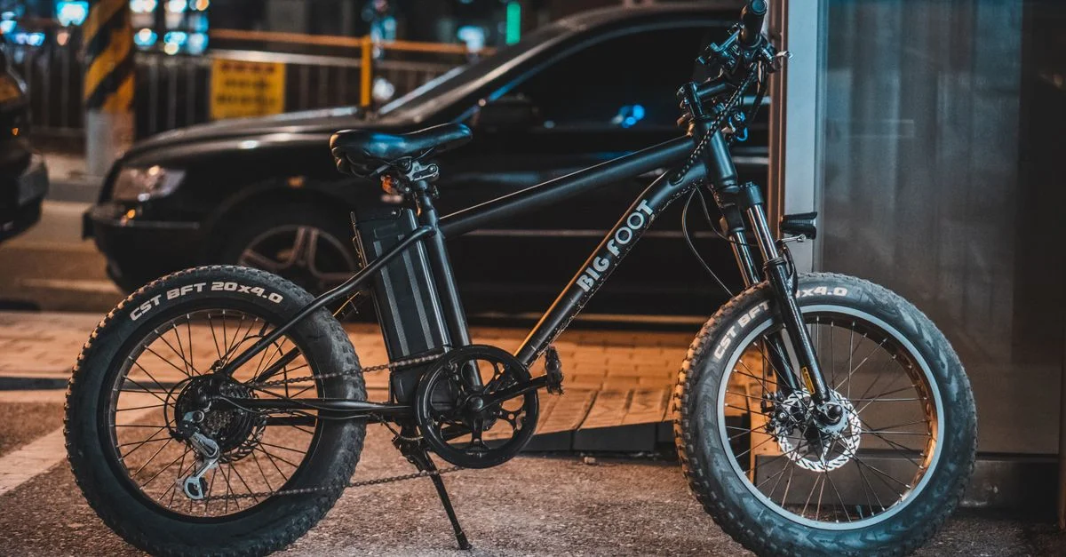 Un vélo électrique moderne garé sur le trottoir dans un environnement urbain la nuit, mettant en avant la technologie.