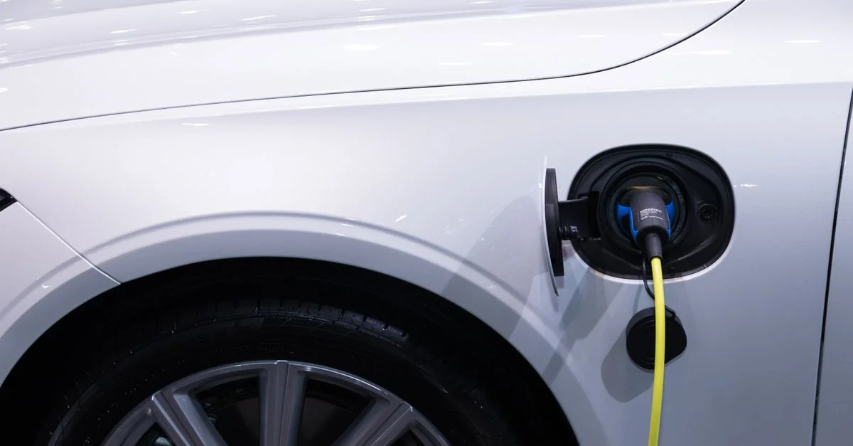 Une voiture électrique blanche est branchée pour se charger, vue en gros plan du port de charge.