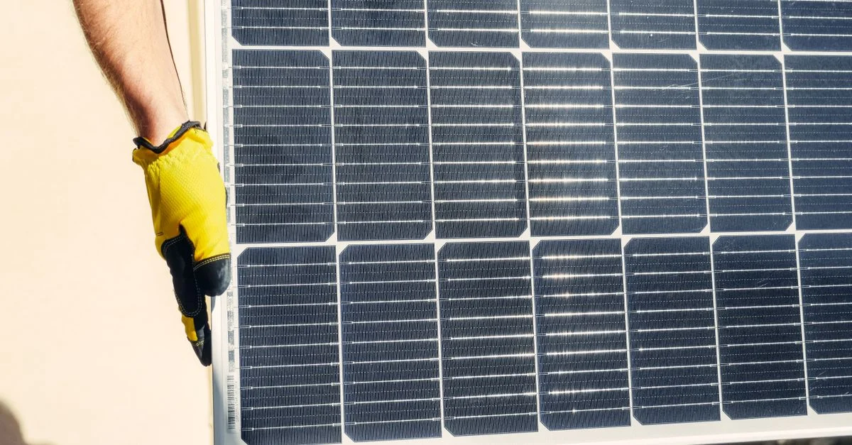Gros plan sur une personne installant un panneau solaire en plein air sous un soleil radieux.